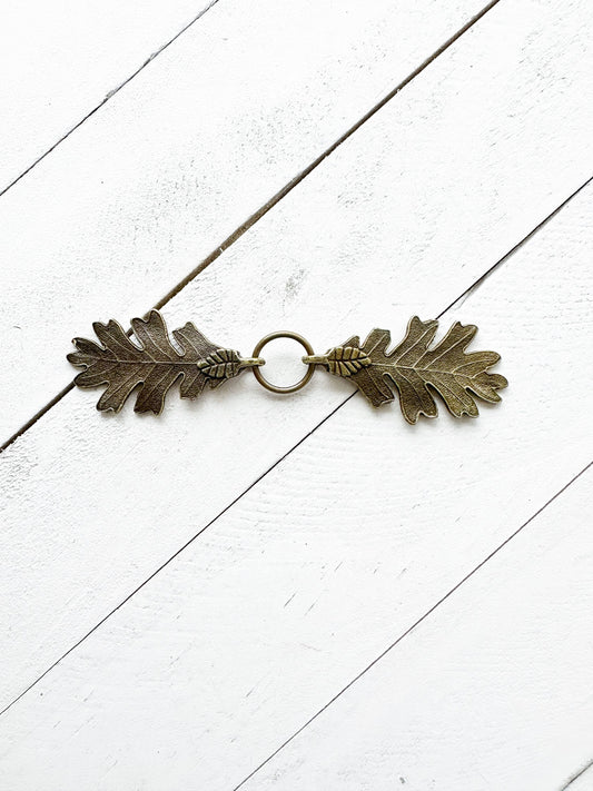 Interlocking bronze oak leaves clasp with center ring, studio shot