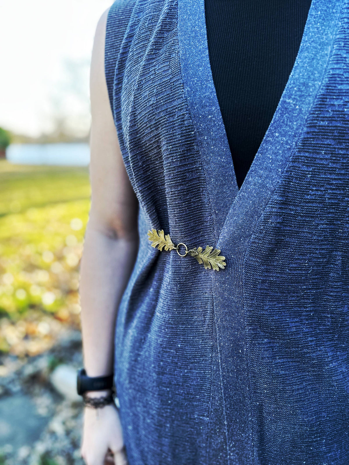 Front view of the bronze oak leaf clasp worn on a blue v-neck vest
