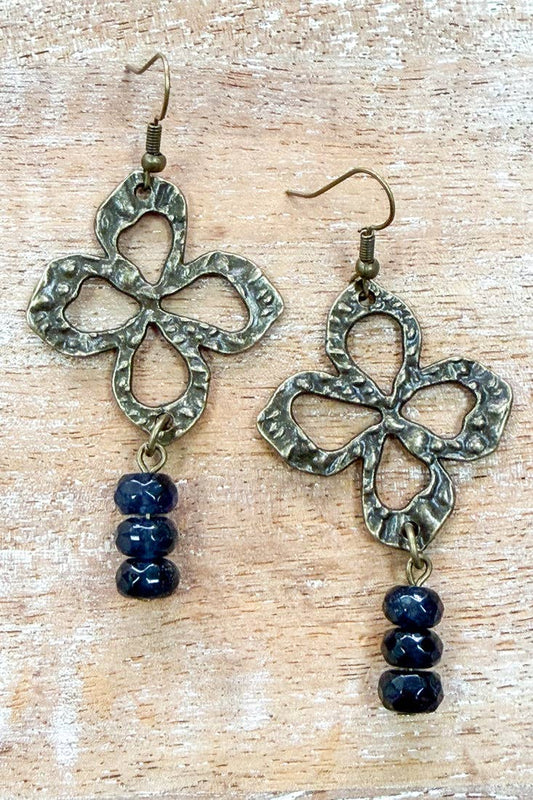 Nisha clover drop earrings on a wood background