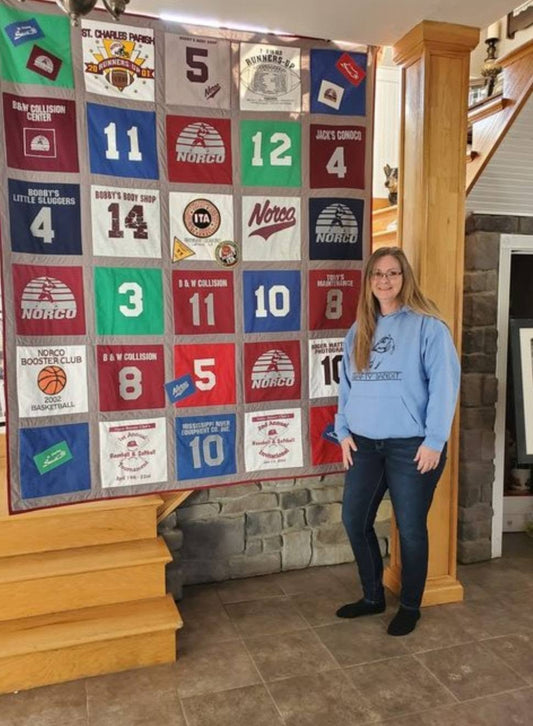Kim, owner of crafty bandit stands near a large patchwork memory quilt she made