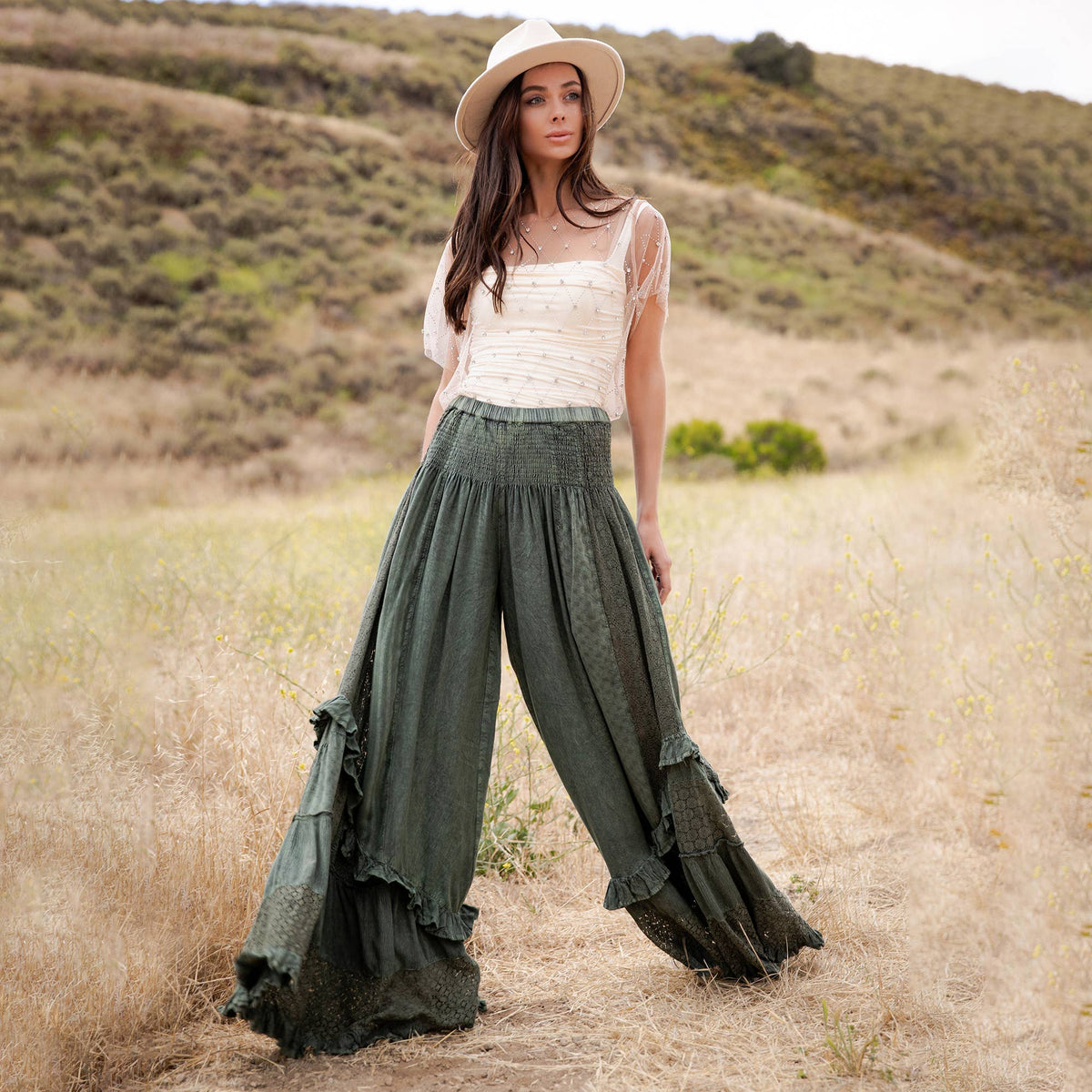 Woman walking in the basil ruffle pants, showing how the wide legs flare