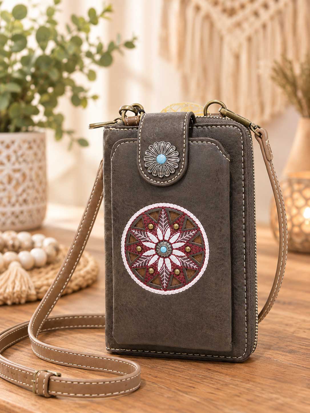Brown crossbody phone wallet with an embroidered floral medallion and concho clasp; this listing is black