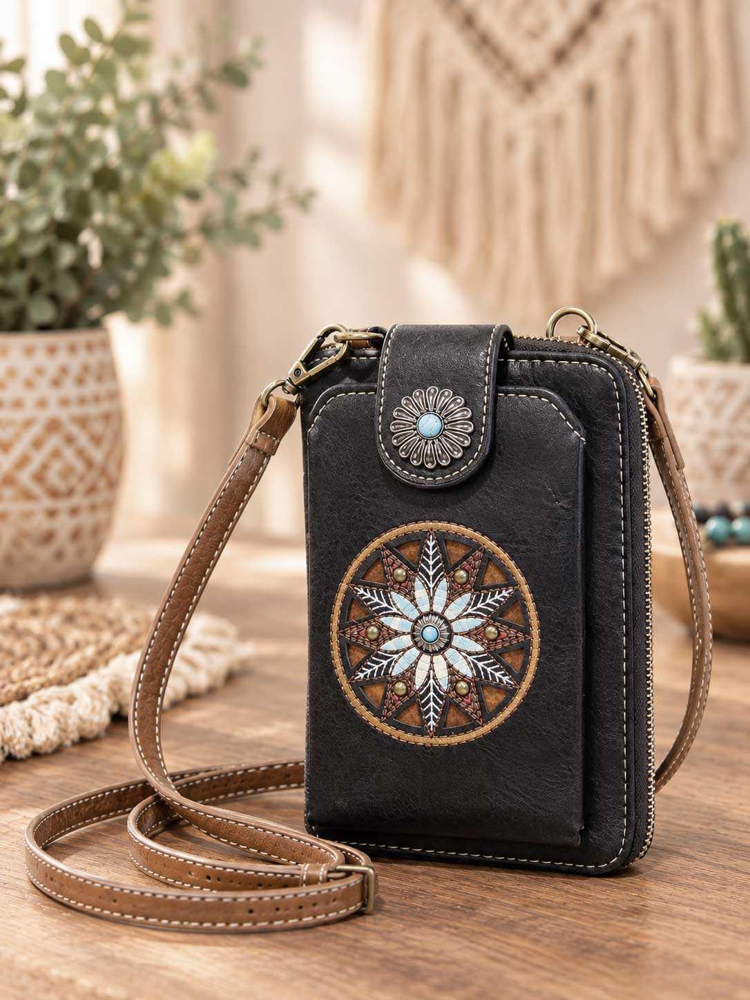 Black crossbody phone wallet with an embroidered floral medallion and concho clasp; this listing is brown