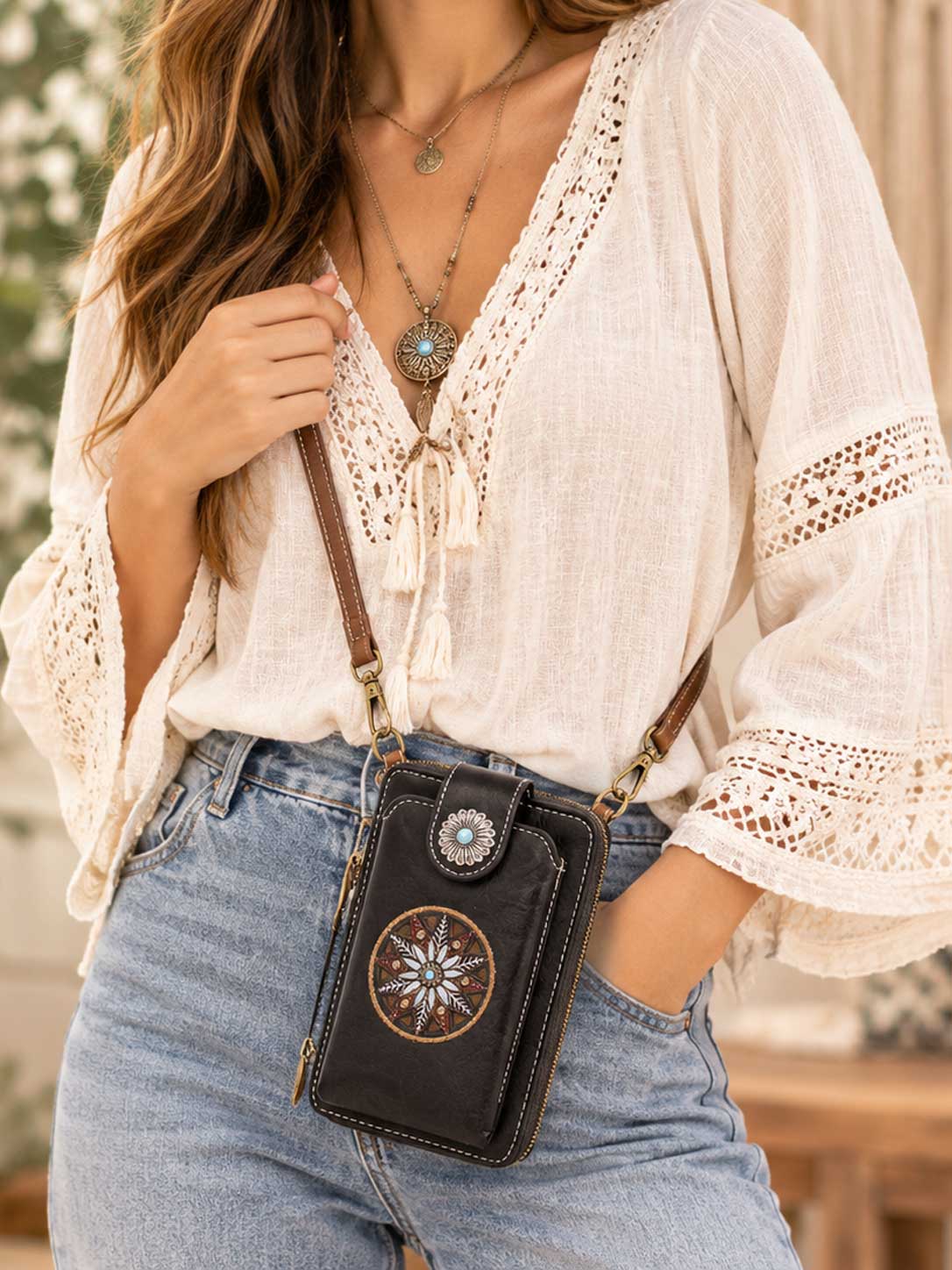 Model wearing the black embroidered medallion phone wallet crossbody