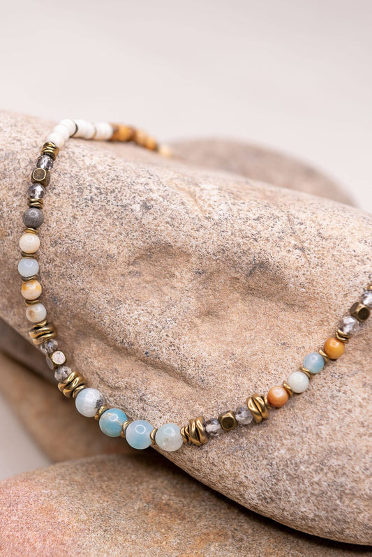 Short beaded choker with amazonite and neutral stone beads draped over a stone