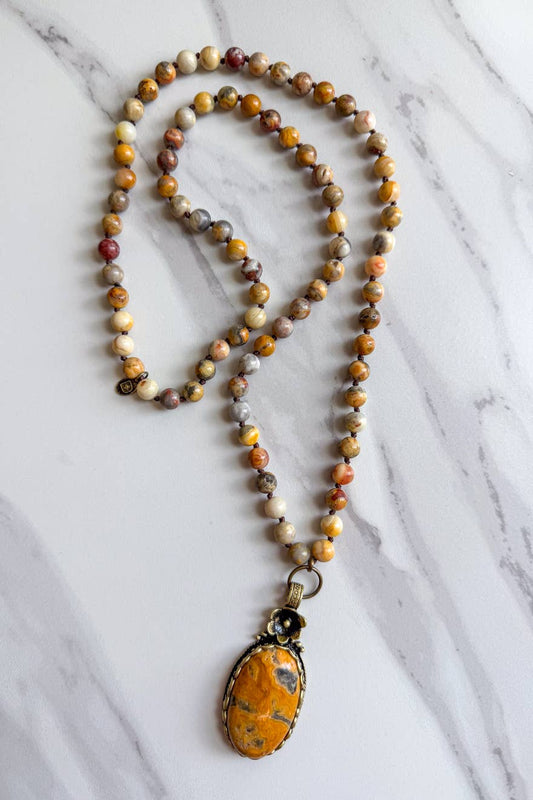 Long knotted bead necklace in tan and brown crazy agate tones with an oval stone pendant