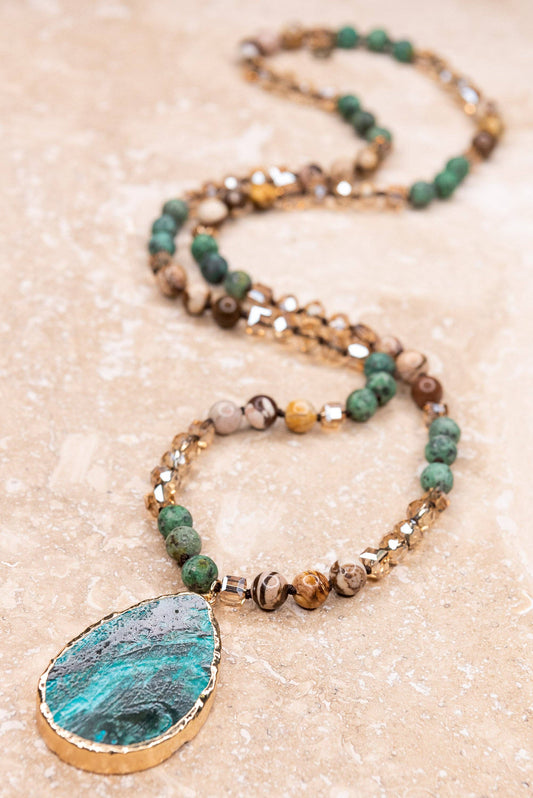 Long knotted crystal and stone bead necklace with a teal teardrop pendant edged in gold