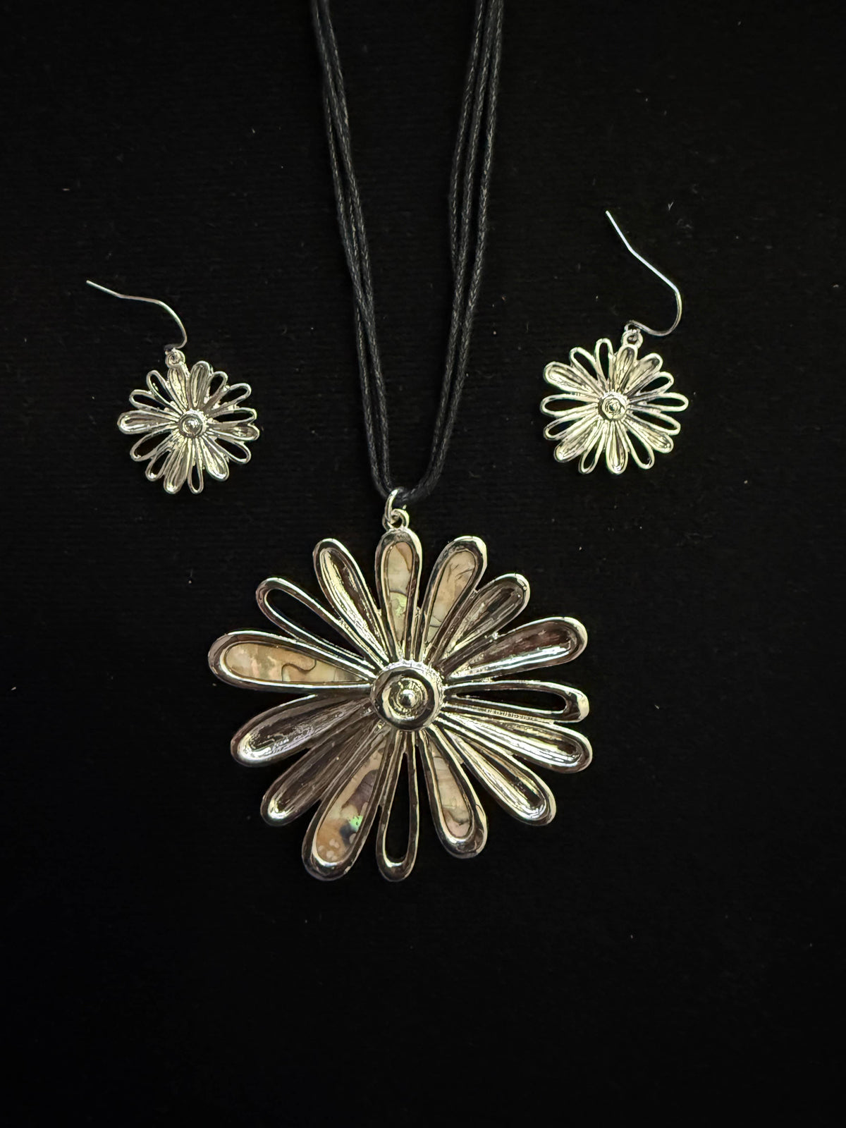 Silver daisy pendant on a black multi-strand cord with matching daisy earrings
