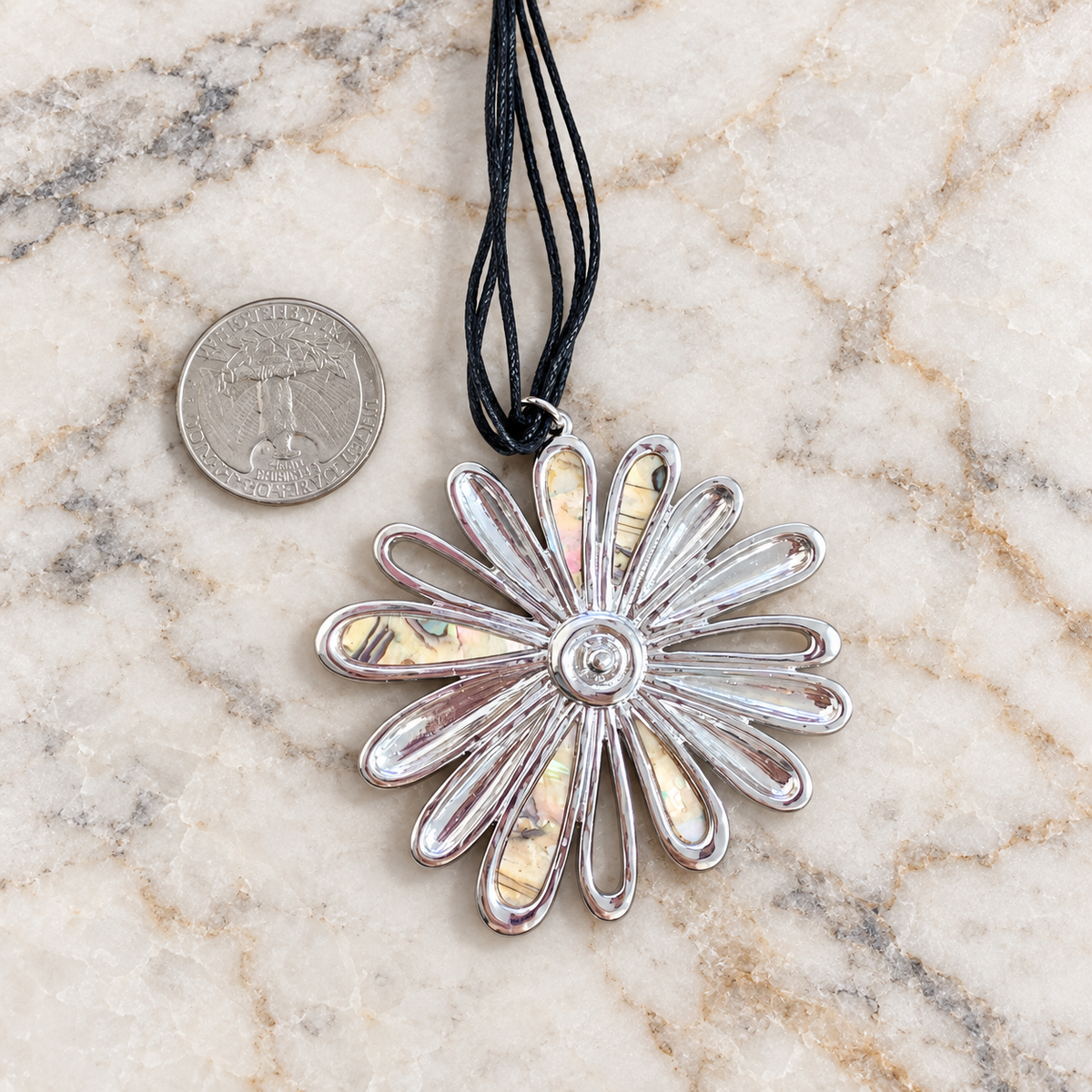 Daisy pendant beside a coin to show its size