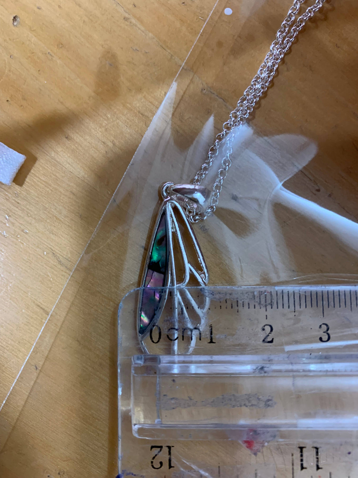 Dragonfly wing pendant next to a ruler for size