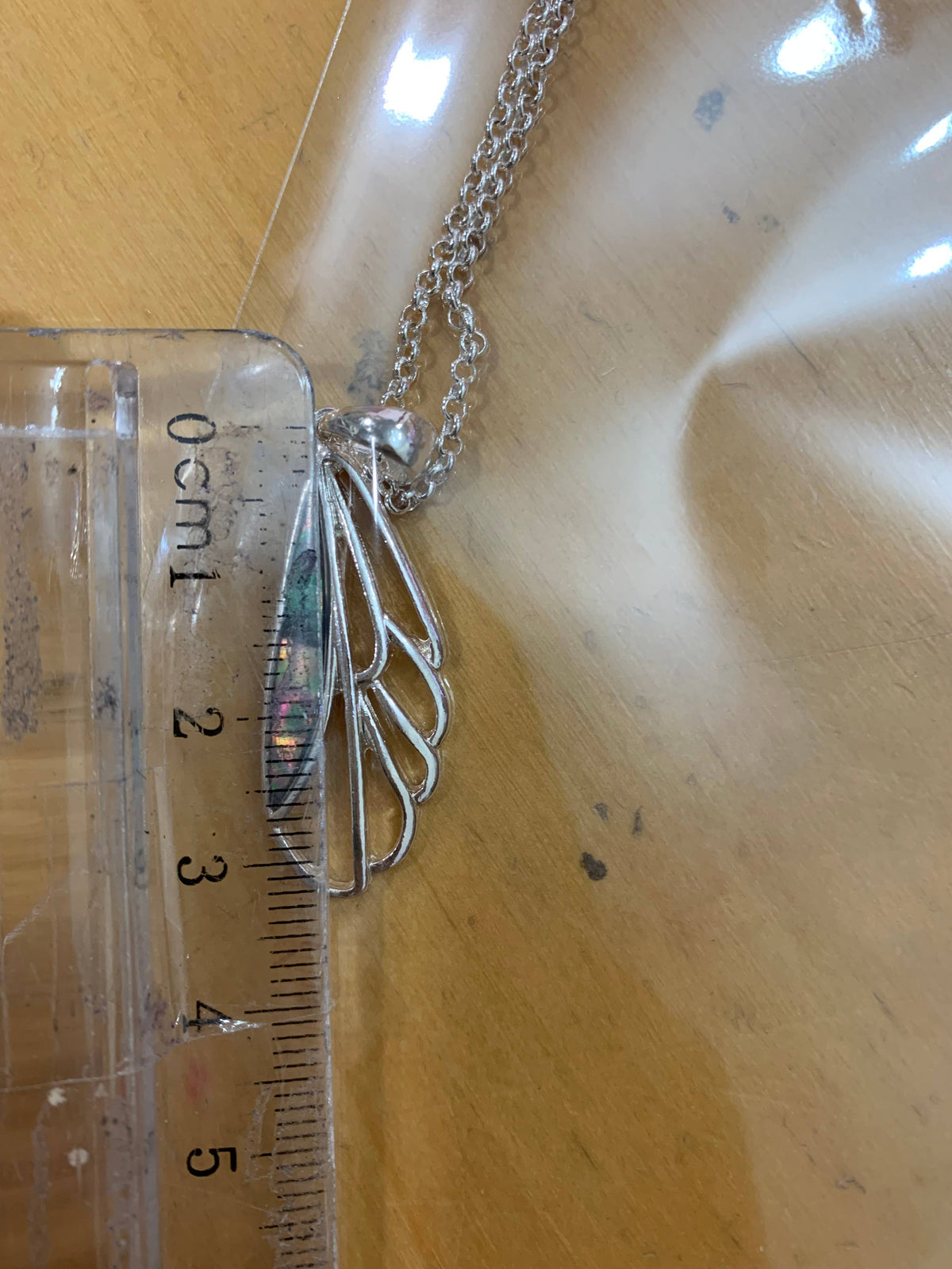 Dragonfly wing pendant measured against a ruler, second view