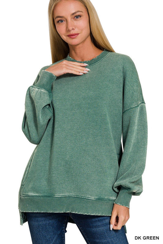 Model in an oversized acid wash fleece pullover in a soft sage green with a hi-low raw hem and side seam pockets