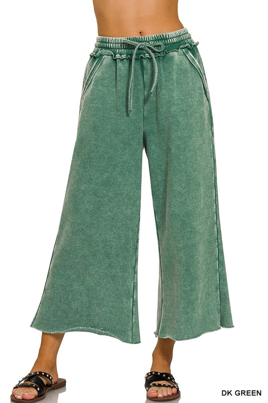 Model wearing acid wash fleece palazzo sweatpants in a washed forest green, drawstring waist and wide leg over black slides