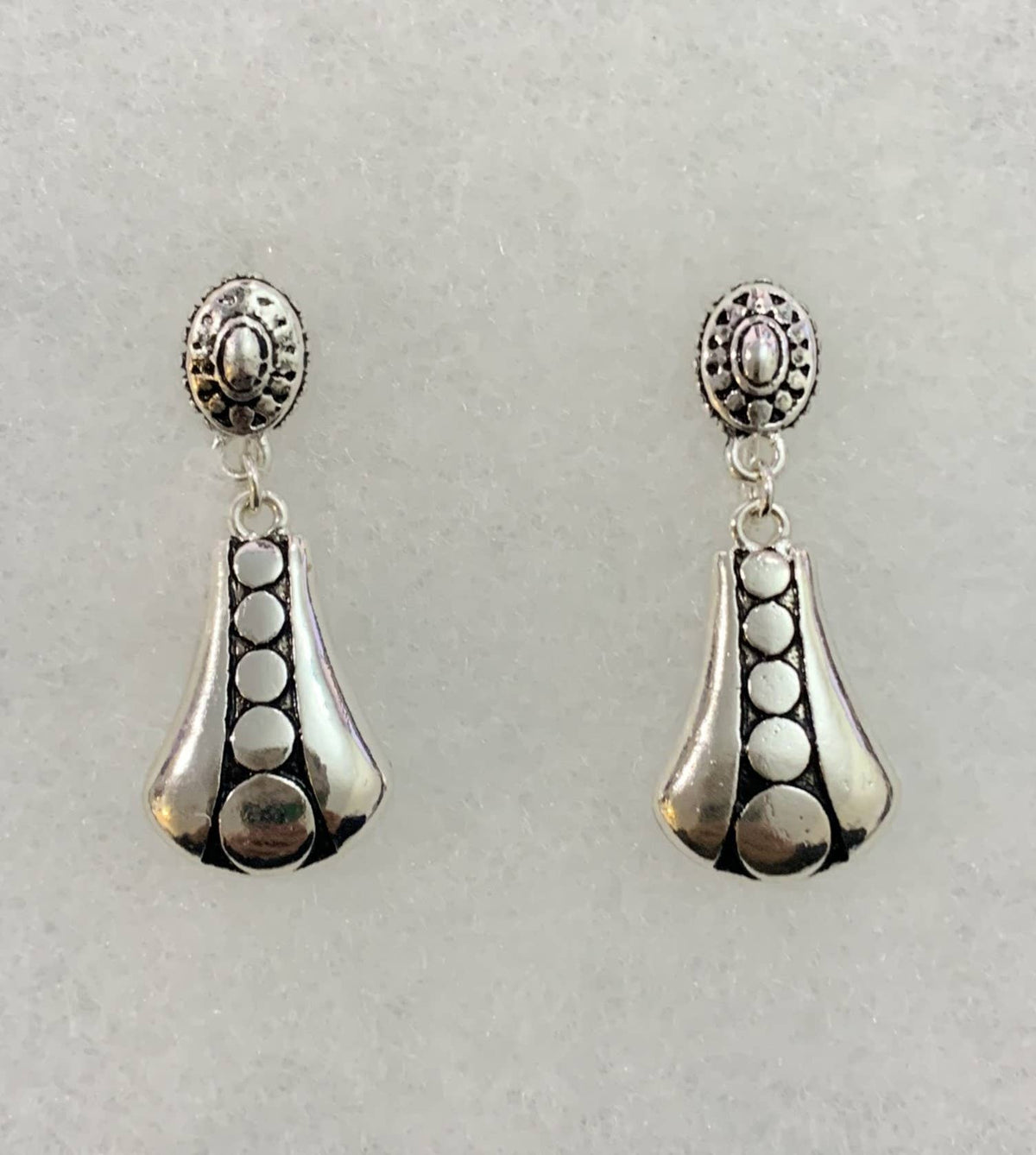 Antique silver clip-on earrings with an engraved circle pattern, front view