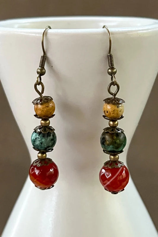 Austin three-stone dangle earrings displayed on a white vase