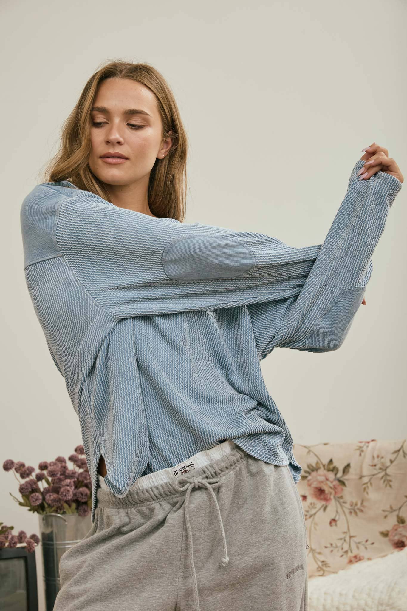 Stretch pose showing the relaxed drape of the light denim top