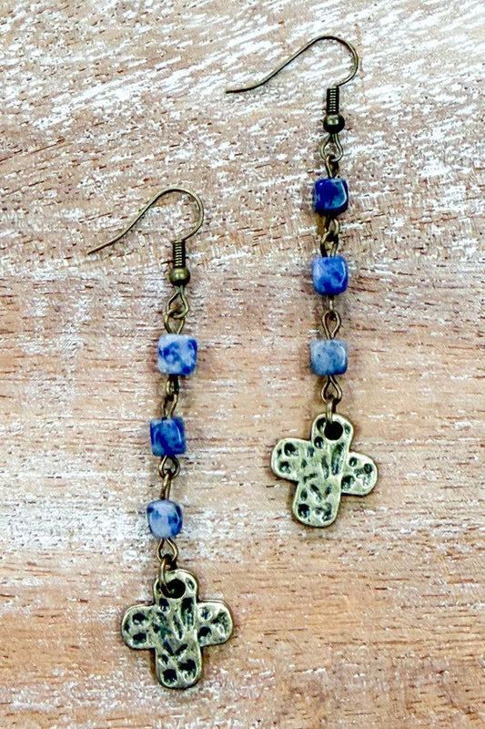 Joan blue bead drop earrings on a wood background