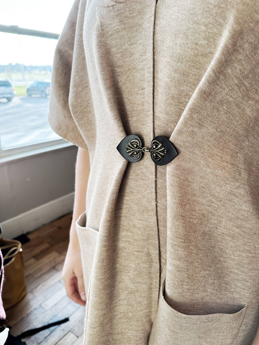 Black cinch clip with bronze filigree gathering an oatmeal duster cardigan at the side