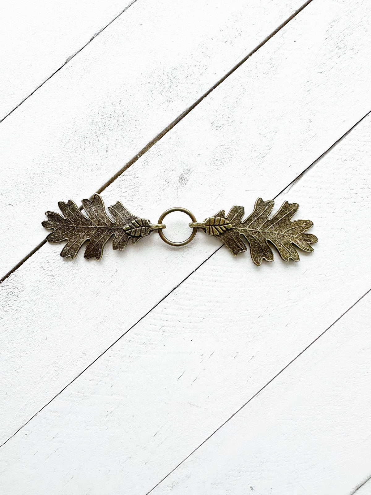 Interlocking bronze oak leaves clasp with center ring, studio shot