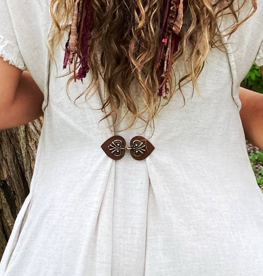 Back view of a flowy white dress cinched at the waist with the dark brown leather cinch clip