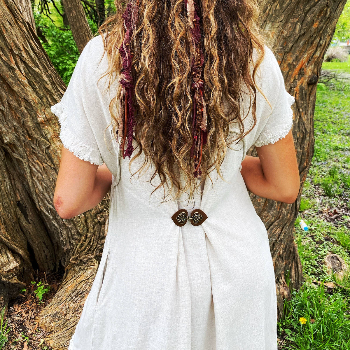 Full back view of the white dress gathered with the dark brown cinch clip, worn outdoors