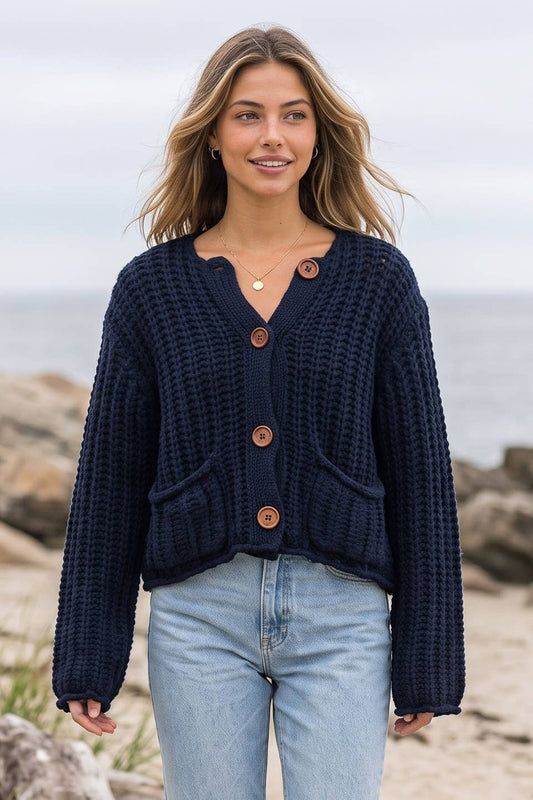 Model wearing the navy chunky knit cardigan with wood buttons and patch pockets at the beach
