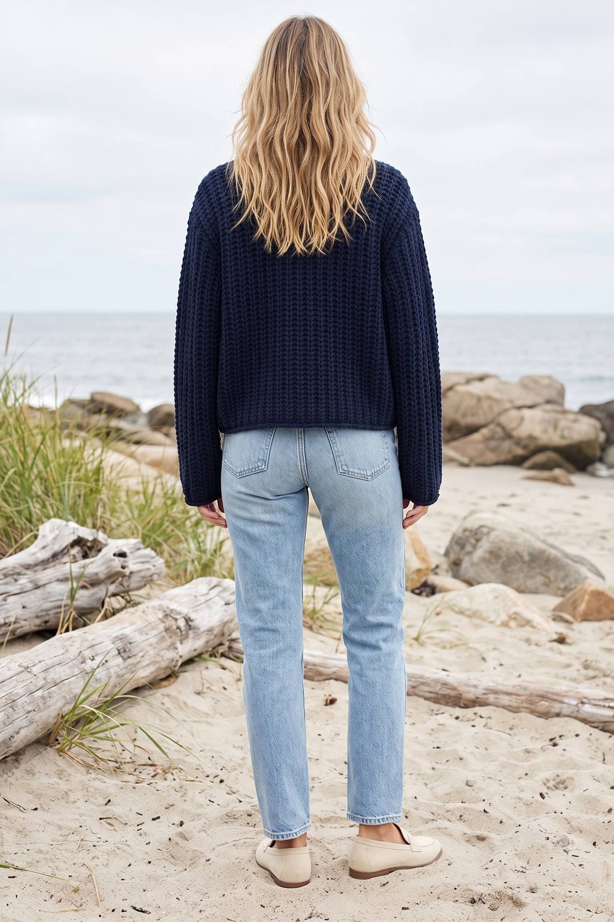 Back view of the navy chunky knit cardigan with light-wash jeans
