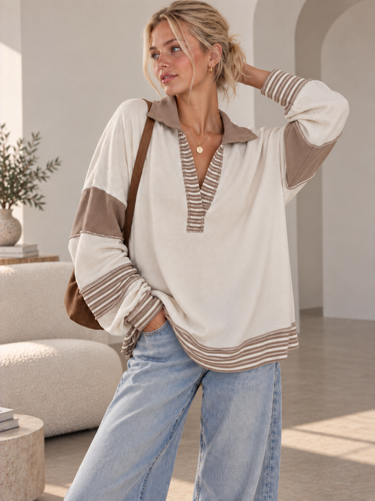 Woman in a cream French terry polo collar top with tan contrast sleeve panels and striped trim, front view