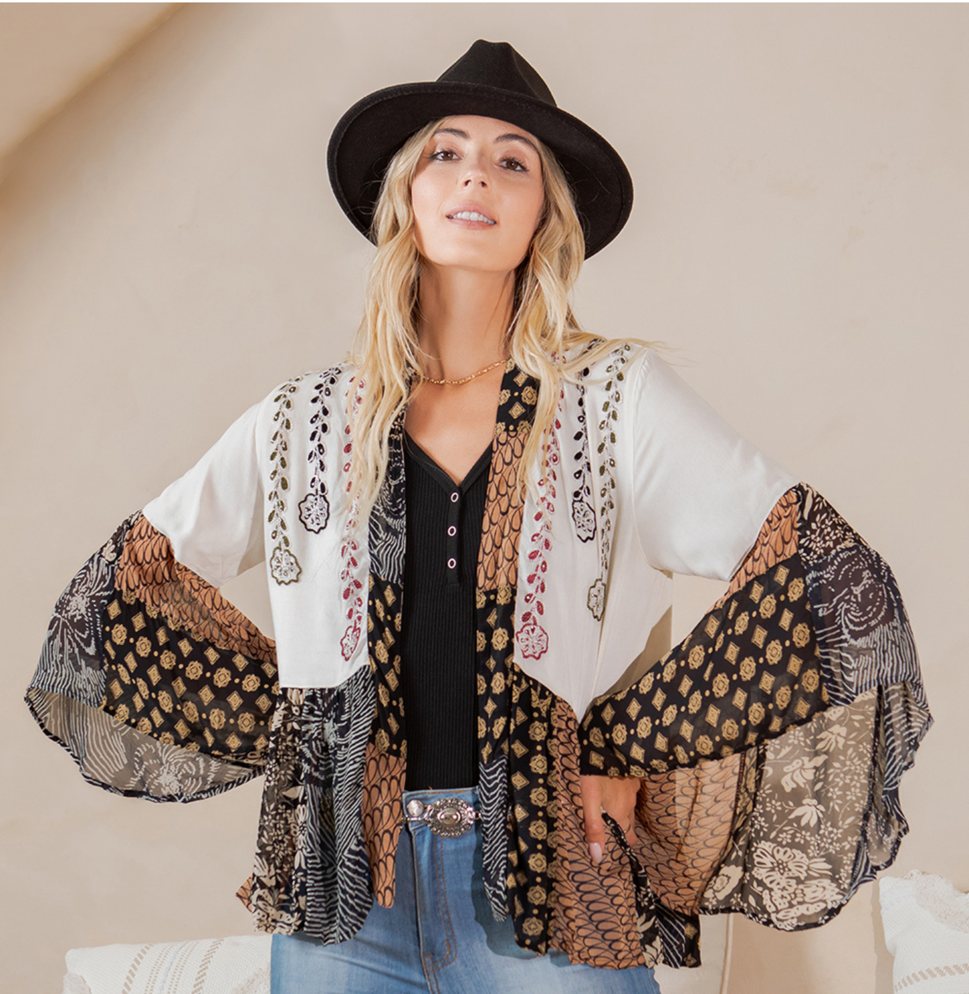Front view with arms out showing the shrug's dramatic flared patchwork sleeves
