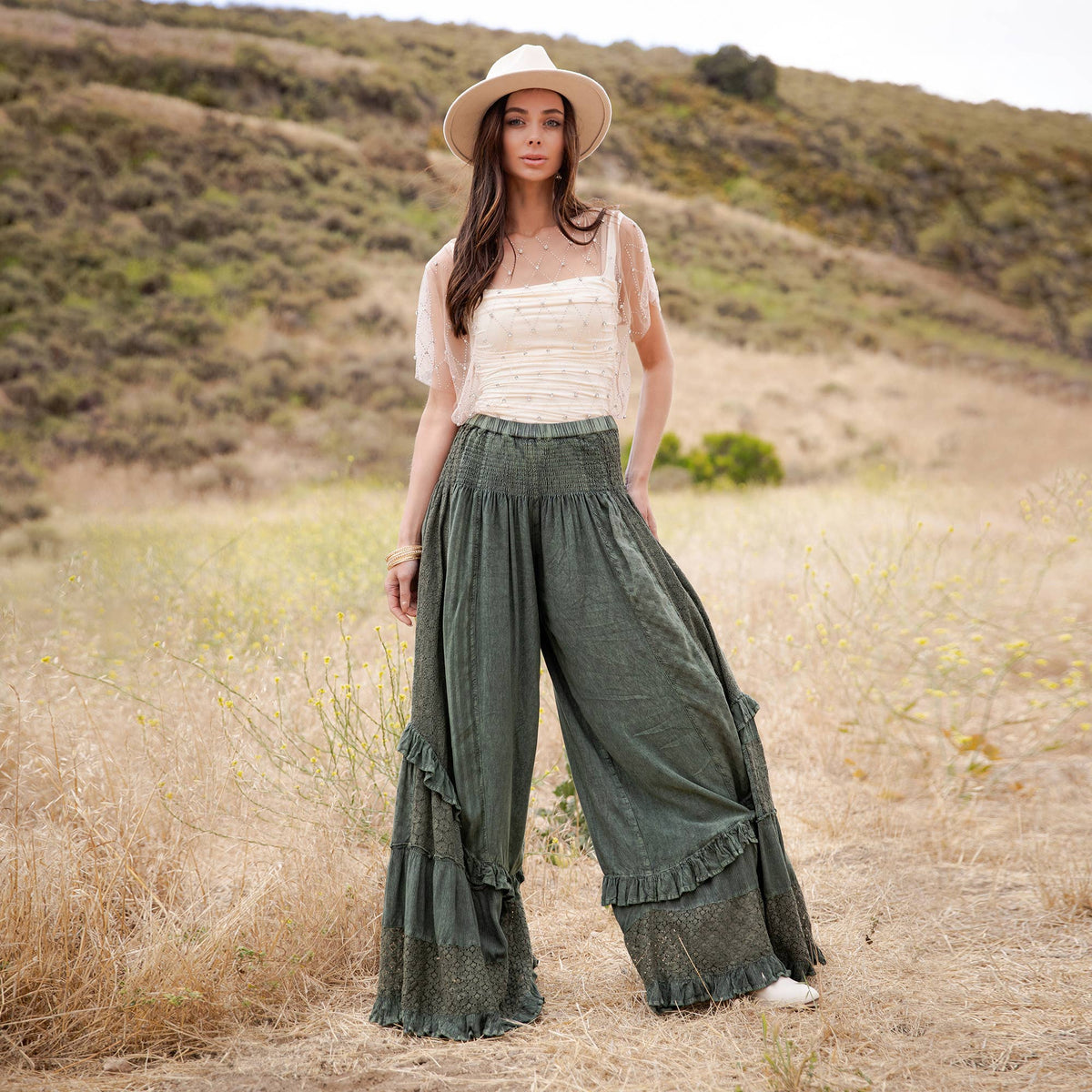 Woman in a straw hat standing in the basil smocked ruffle pants