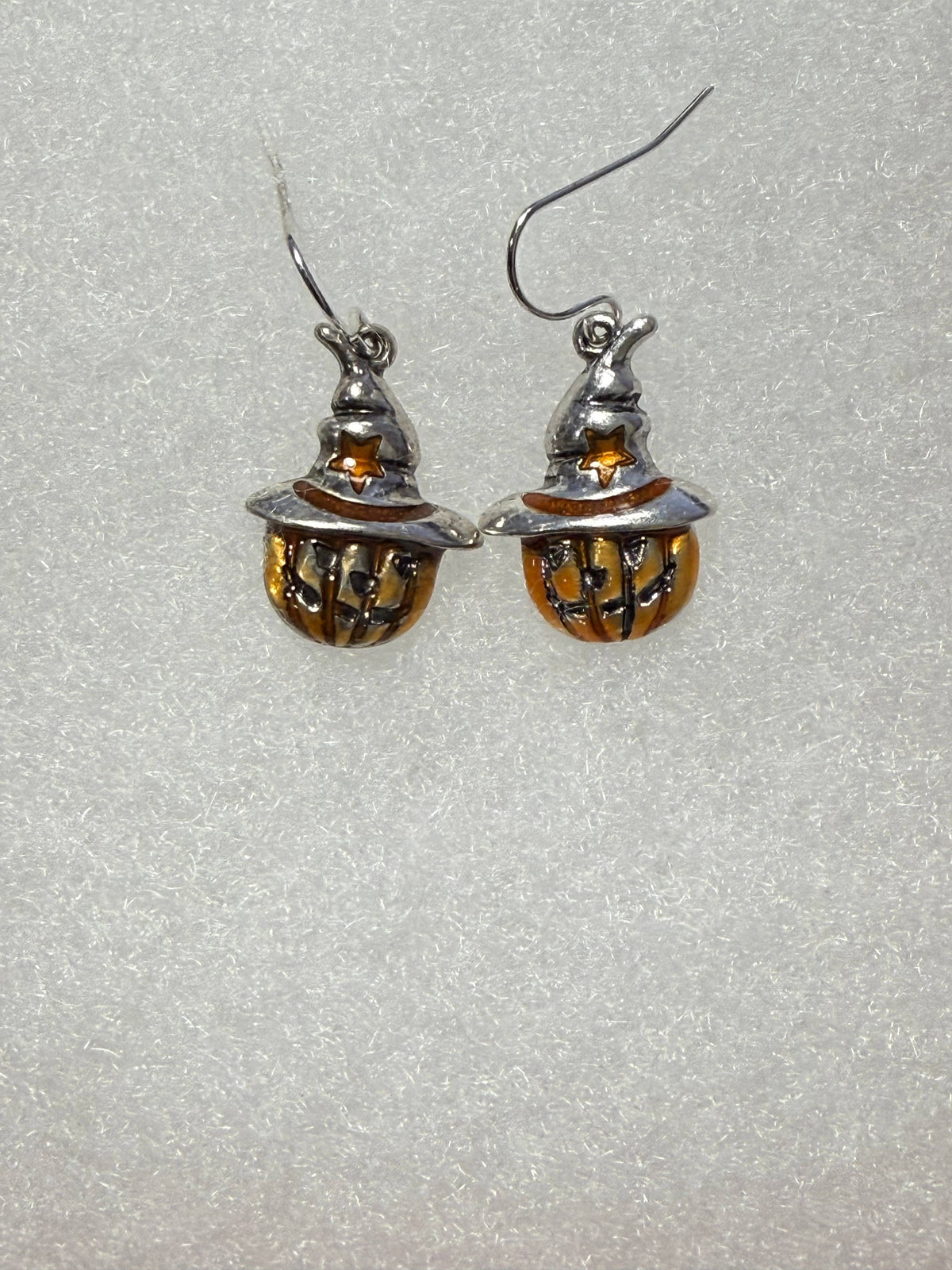 Pumpkin earrings on fish hooks against a gray background