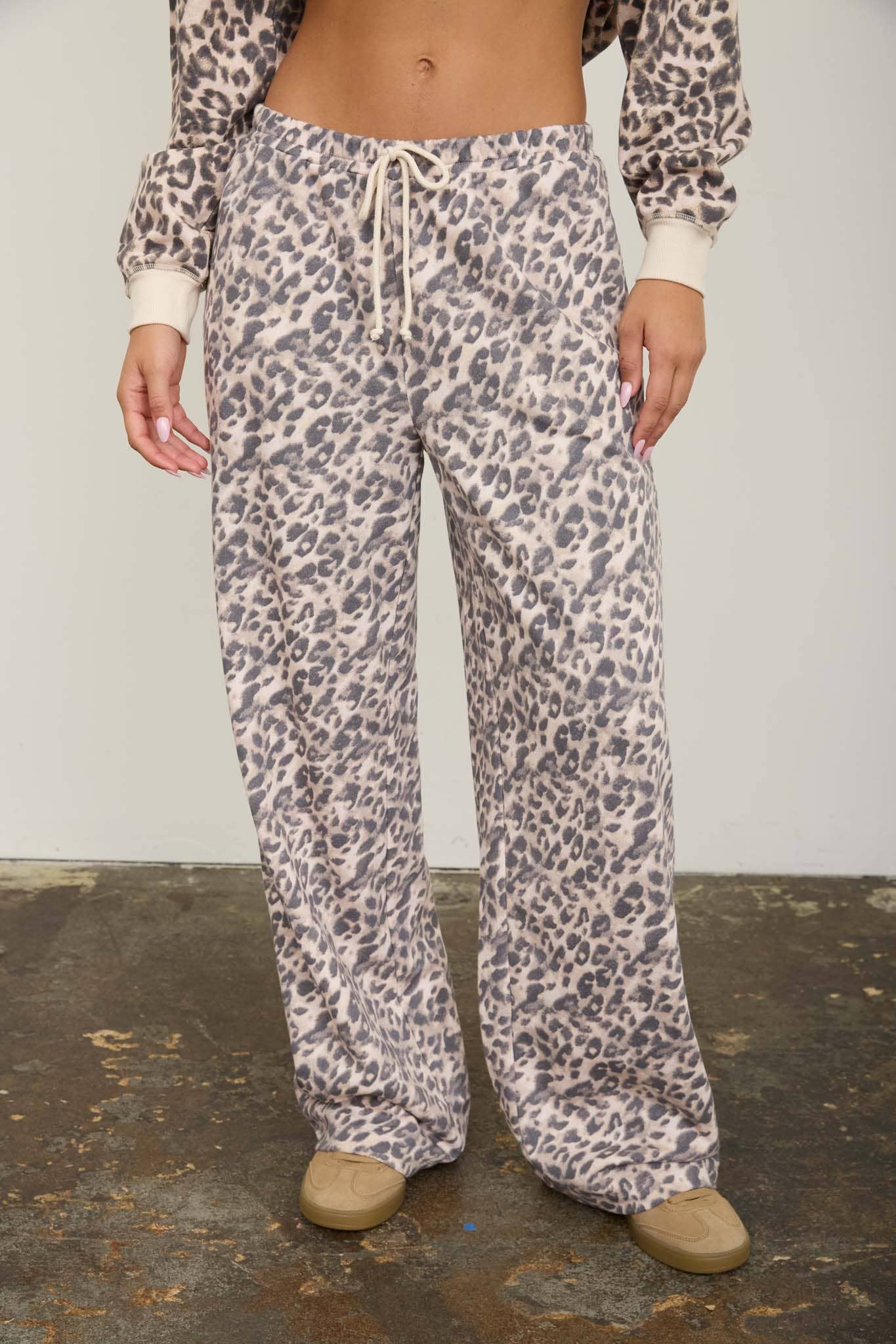 Model in cream and taupe leopard print wide leg lounge pants with a drawstring waist, front view, worn with the matching leopard top