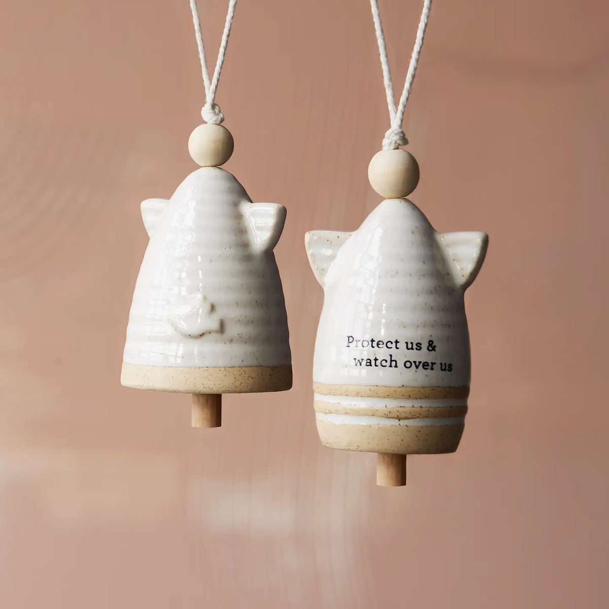 Two cream angel shaped mini bells hanging together with the words Protect us and watch over us