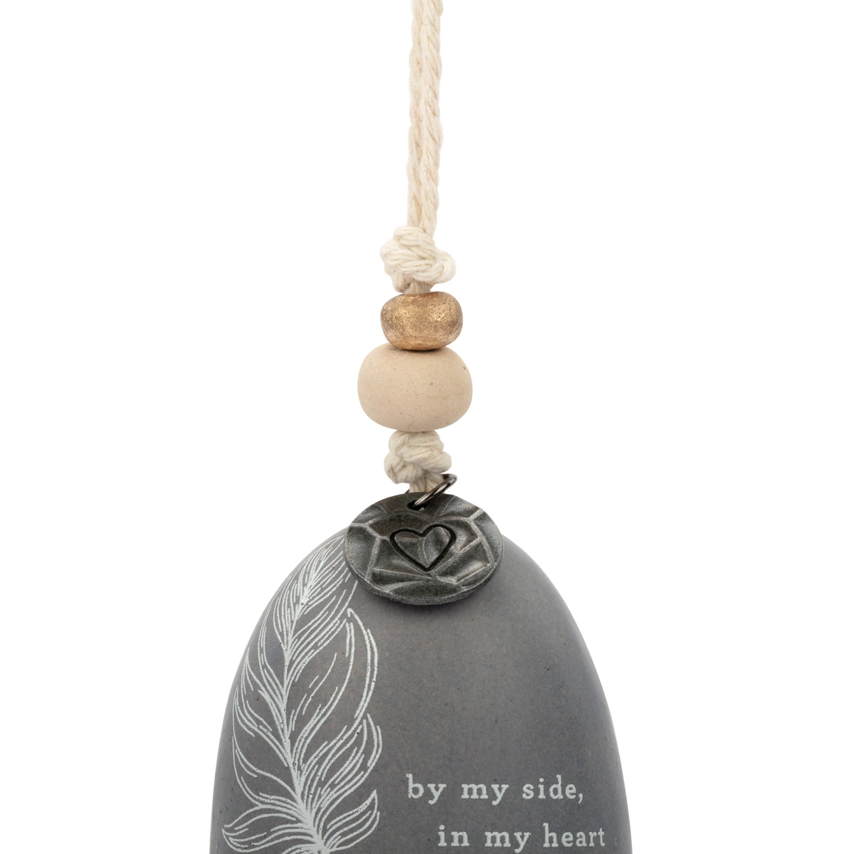 Close-up of the gray Mini Inspired Bell with a white feather and the words By my side, in my heart