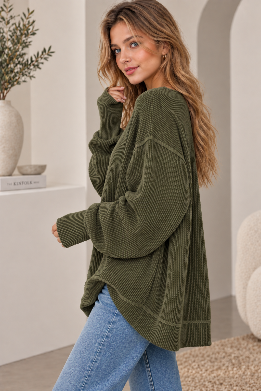 Woman in an oversized olive ribbed knit crewneck sweatshirt with jeans, side view