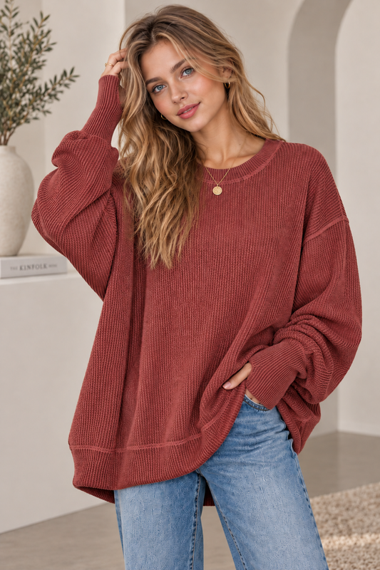 Woman in an oversized rust ribbed knit crewneck sweatshirt with jeans, front view