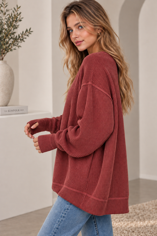 Woman in an oversized rust ribbed knit crewneck sweatshirt with jeans, side view
