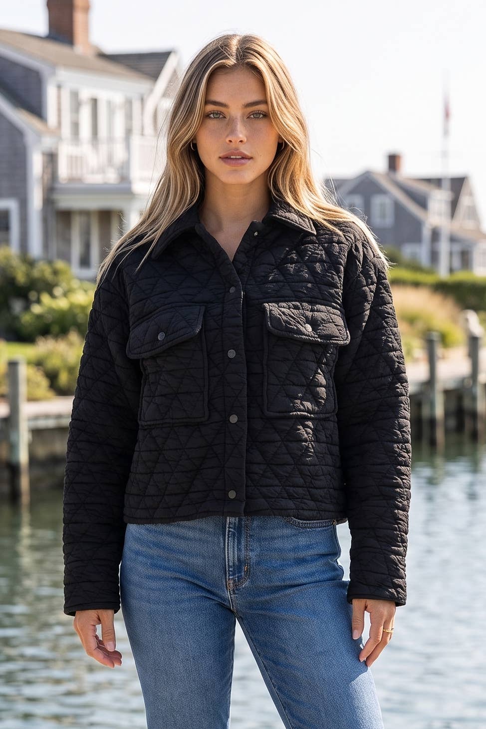Woman wearing the black quilted snap front jacket with a point collar and flap chest pockets over jeans