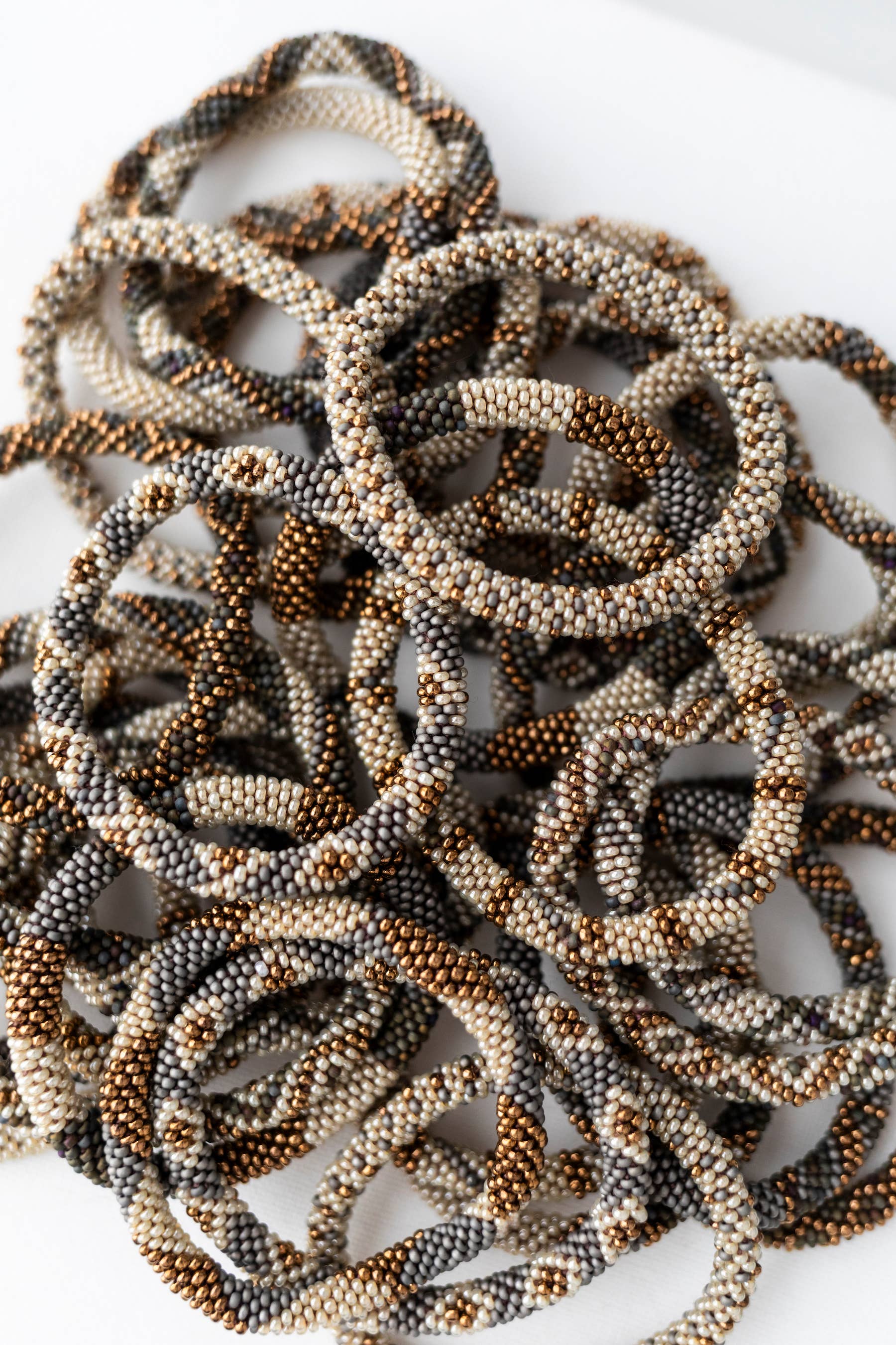 Overhead pile of hazel glass bead bracelets in woodland browns and creams