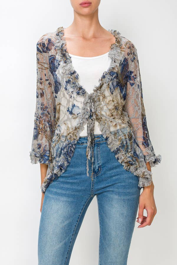 Model wearing a sheer blue and gold floral lace tie-front cardigan over a white cami with jeans