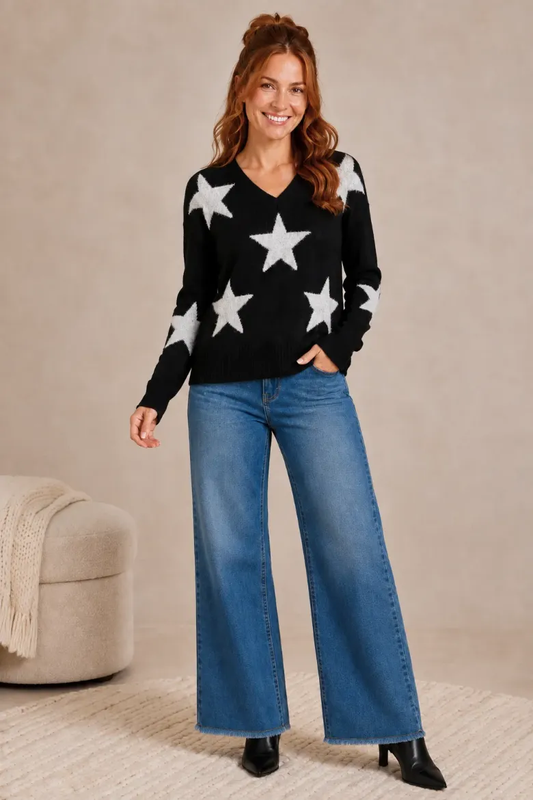 Woman wearing the black star jacquard V-neck fuzzy sweater with wide-leg jeans