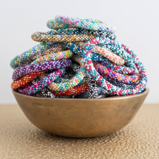 Assorted bright multicolor glass bead roll-on bracelets piled in a brass bowl