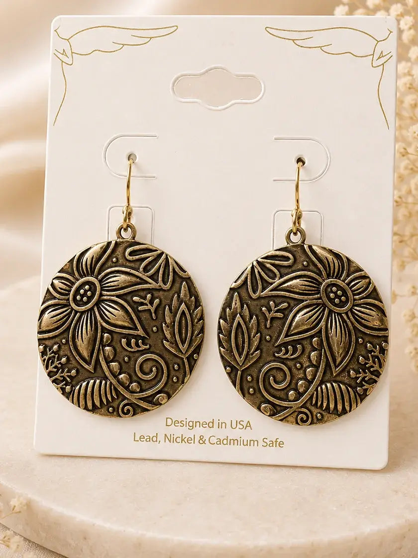 Worn gold sunflower disc earrings on a display card