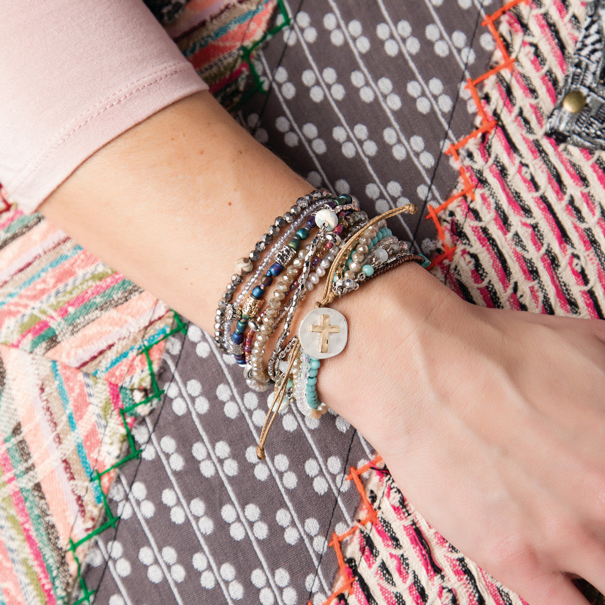 Close view of the turquoise prayer bracelet worn on a wrist and stacked with other beaded bracelets